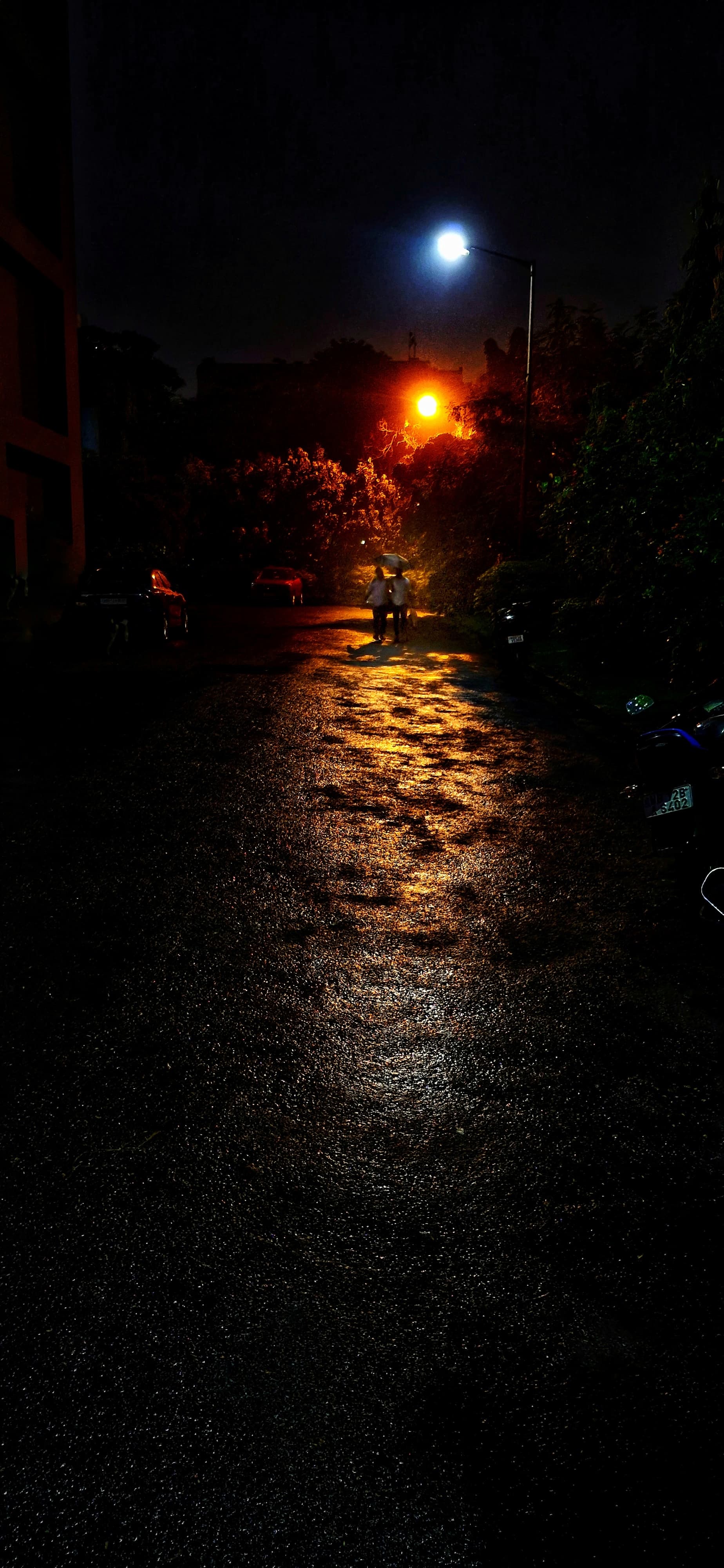 A brightly lit street at night featuring a parked motorcycle under streetlights.