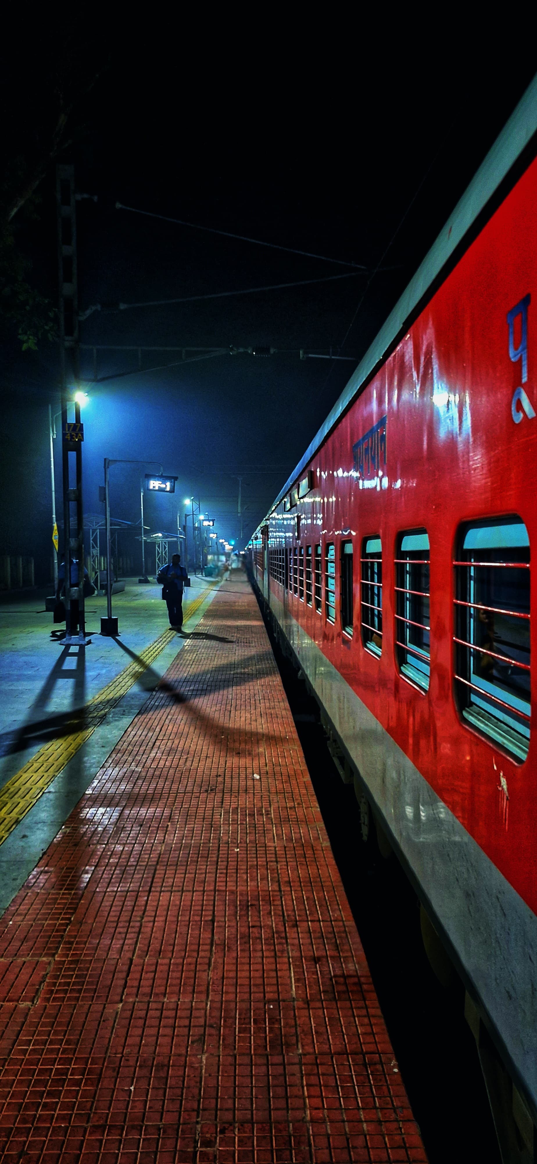 A train is parked at a dimly lit station, surrounded by shadows and illuminated by station lights at night.